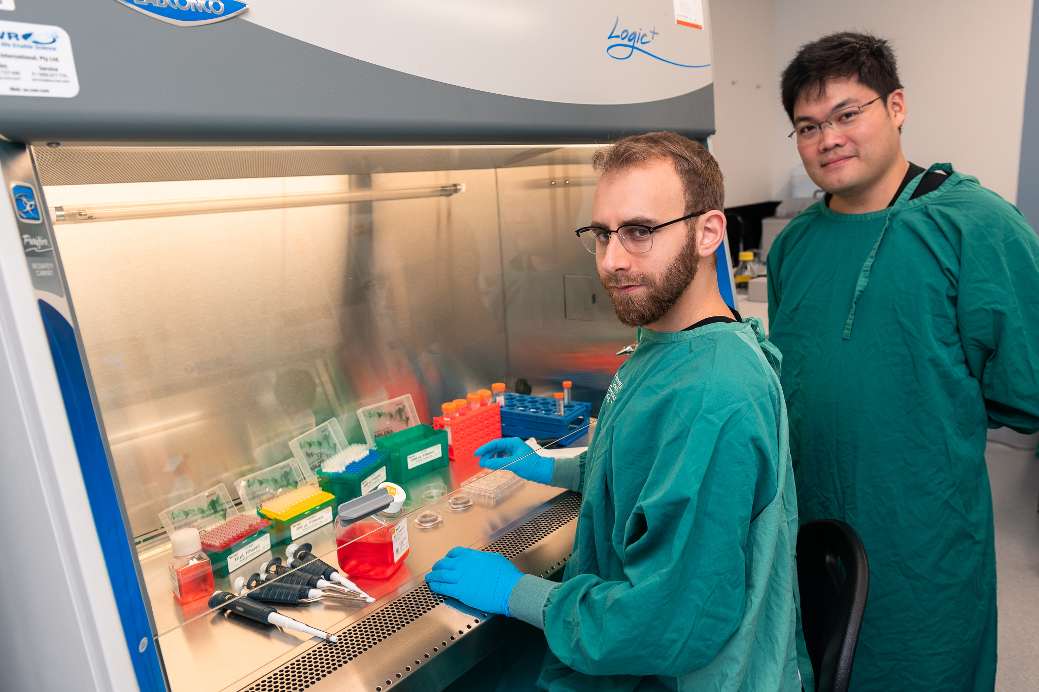 Cortical Labs Dr Brett J. Kagan and Dr Hon Weng conducting cell work on multi-electrode arrays in a biosafety hood